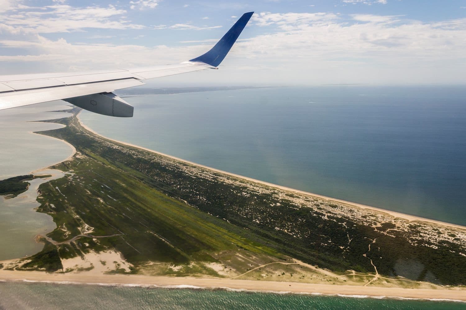 View of plane wing and Nantucket water and land from plane window.