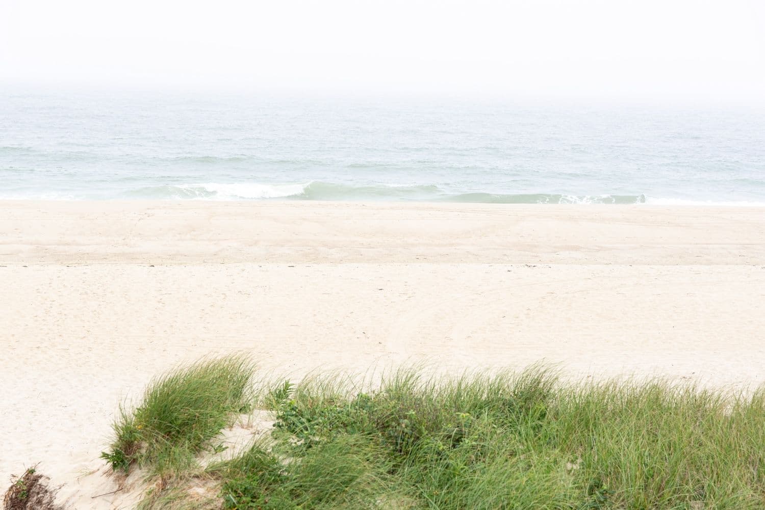 White sand beach with water and dunes.