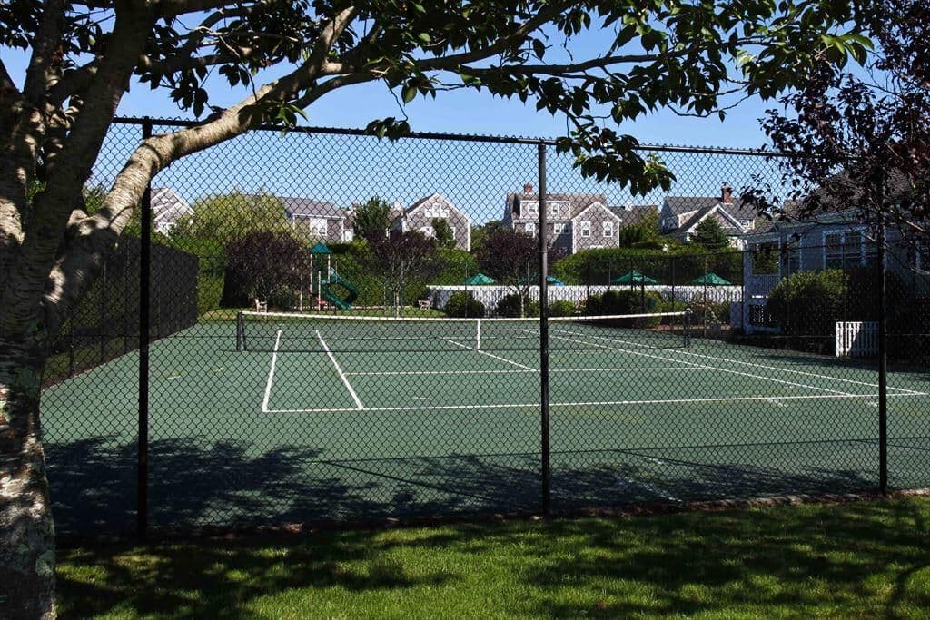 Straight on view of Naushop tennis court with houses in background.